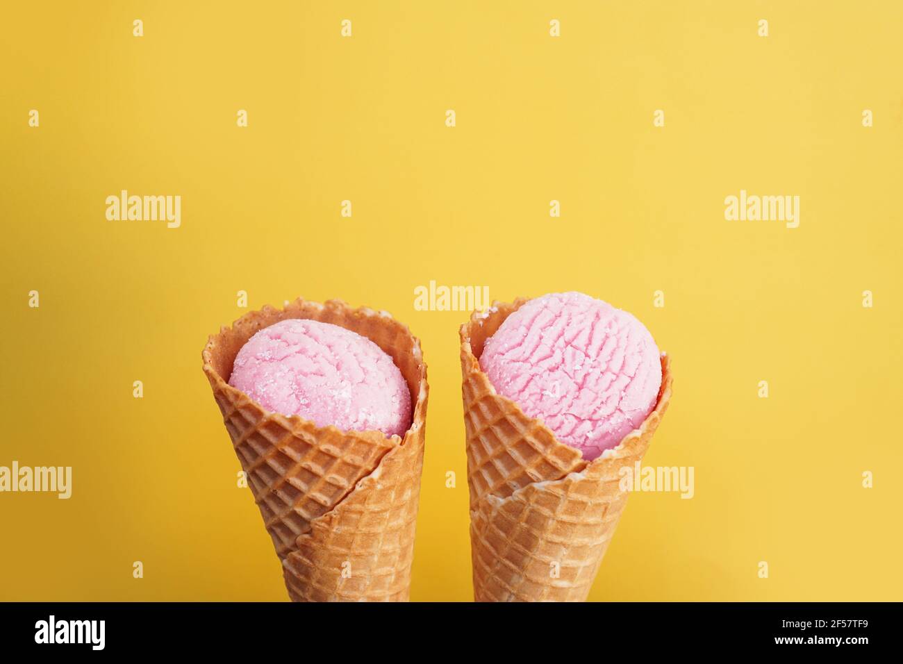 Köstliches rosa Eis in einem Kegel auf gelbem Hintergrund. Stockfoto