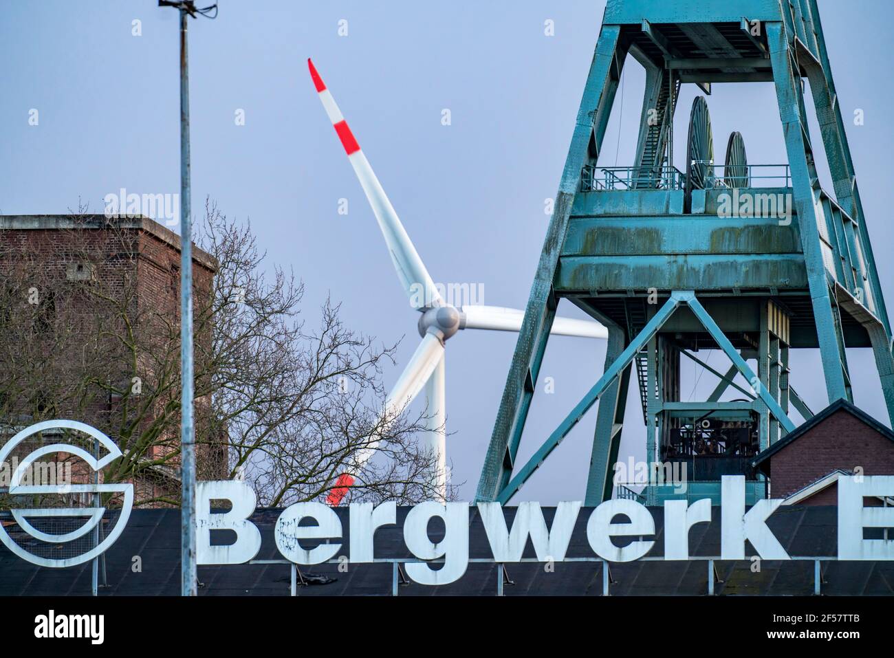 Ehemaliges RAG Ewald-Bergwerk, Wickelrahmen, Schacht 7, Doppeltreste, dahinter das Windkraftwerk auf dem Hoppenbruch in Herten, NRW Stockfoto