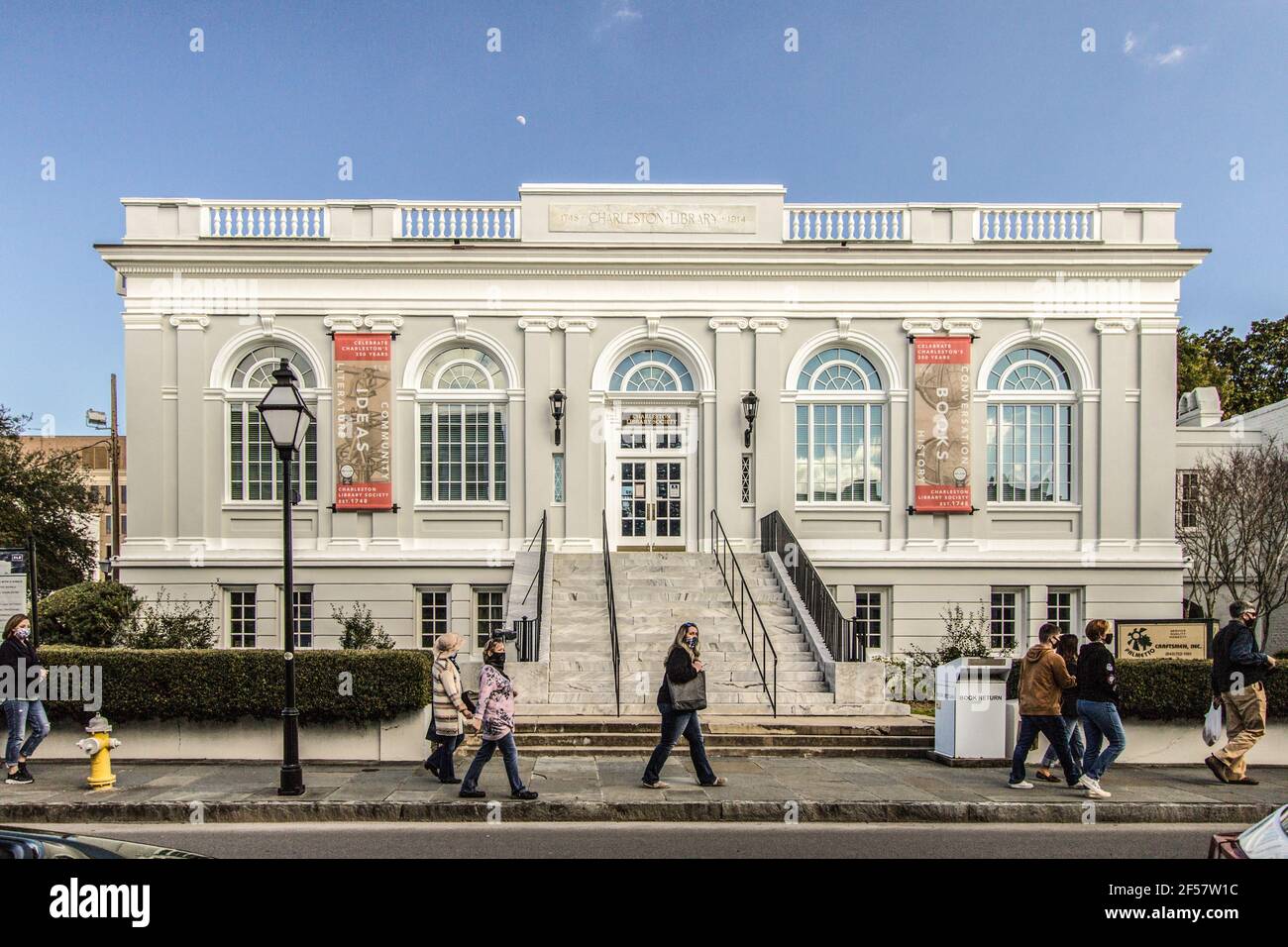Charleston, South Carolina, USA - 20. Februar 2021:Maskierte Touristen flanieren an der Fassade der historischen Charleston Library vorbei Stockfoto