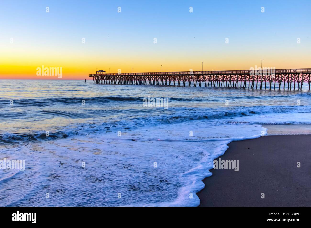 Myrtle Beach Landschaft Bei Sonnenaufgang. Sonnenaufgang an einem breiten Sandstrand mit Angelpier an der Küste des Atlantischen Ozeans in Myrtle Beach, South Carolina, USA Stockfoto