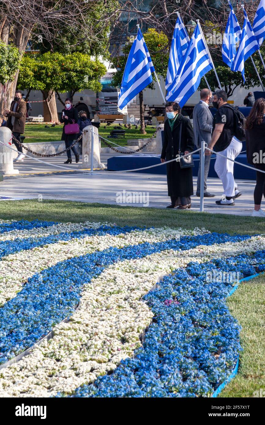 Eine griechische Dame beobachtet die Blumen auf dem Syntagma-Platz in Athen während der Feierlichkeiten zum 200. Jahrestag des griechischen Unabhängigkeitskrieges (25 1821.-2021. März). Stockfoto