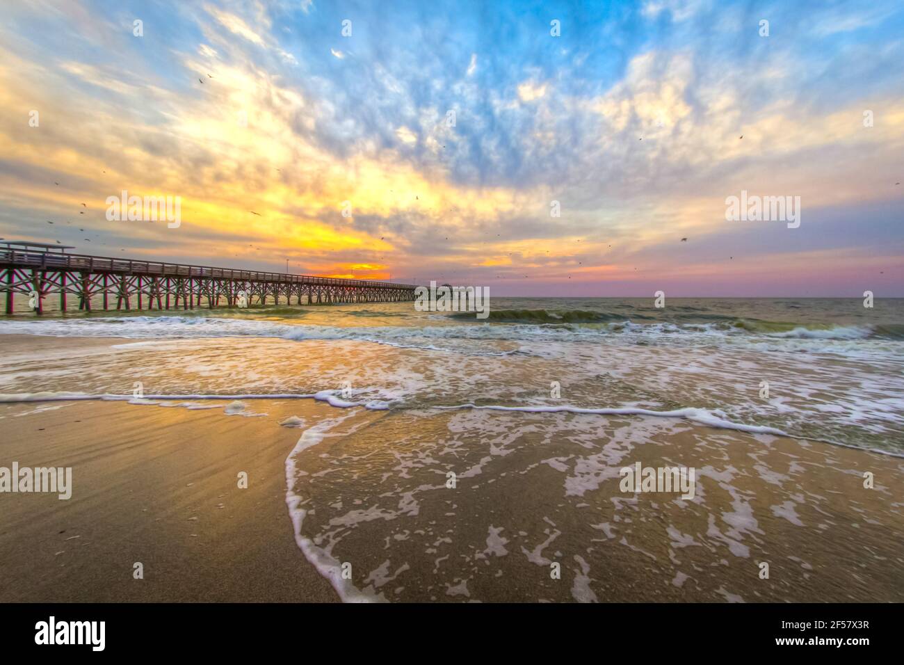 Myrtle Beach Landschaft Bei Sonnenaufgang. Sonnenaufgang an einem breiten Sandstrand mit Angelpier an der Küste des Atlantischen Ozeans in Myrtle Beach, South Carolina, USA Stockfoto