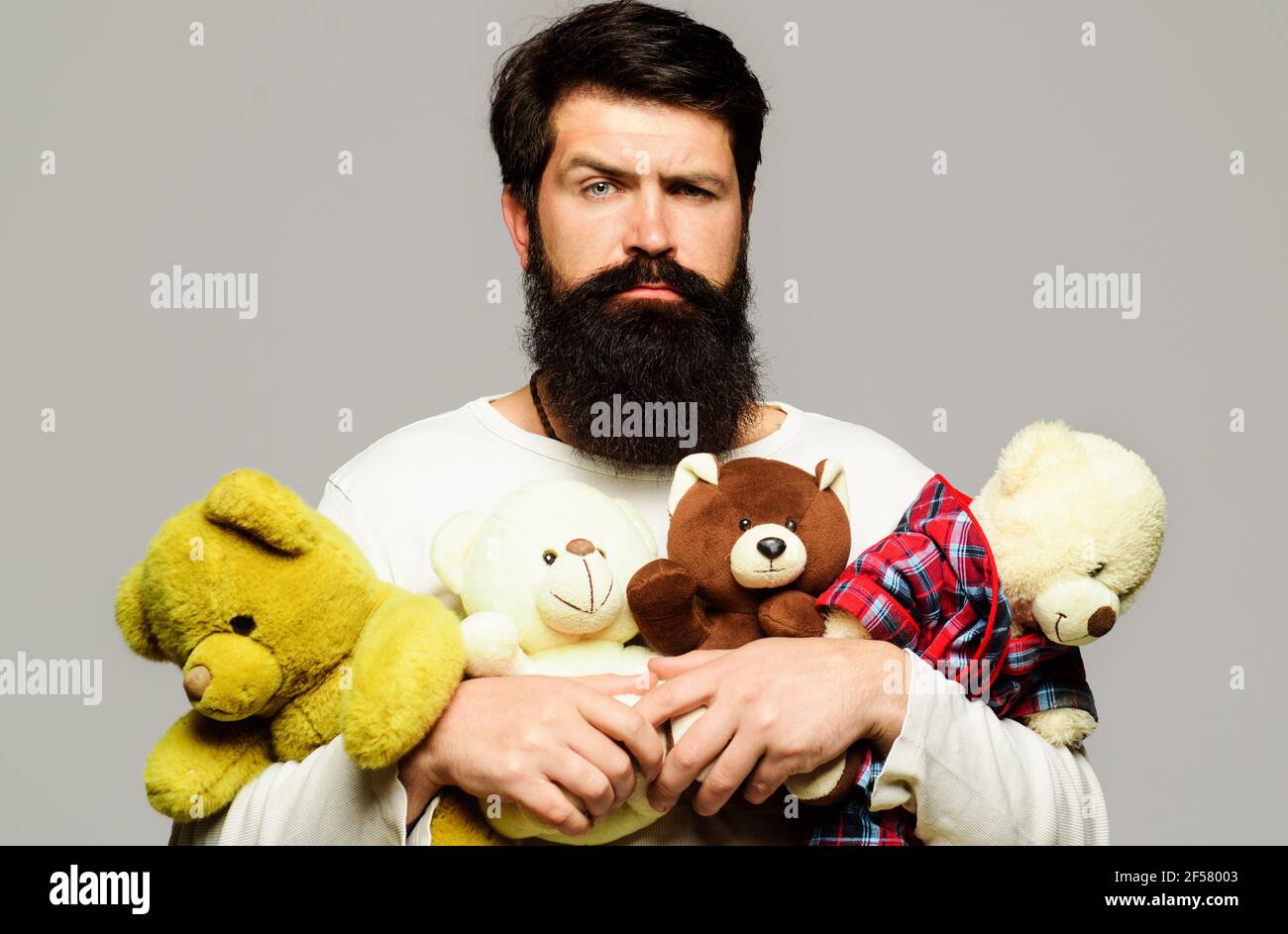 Ernsthafter bärtiger Mann, der Teddybär umarmt. Männlich mit Plüsch Spielzeug. Geburtstag, Jahrestag und Feiertagsfeier. Stockfoto