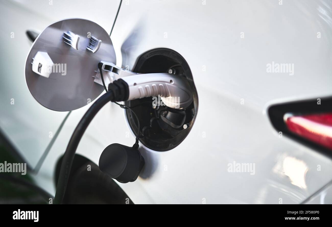 Detail eines Steckers, der an ein Elektroauto angeschlossen ist, das aufgeladen wird Seine Batterien Stockfoto Detail eines Steckers, der an ein Elektroauto angeschlossen ist, das aufgeladen wird Seine Batterien Stockfoto