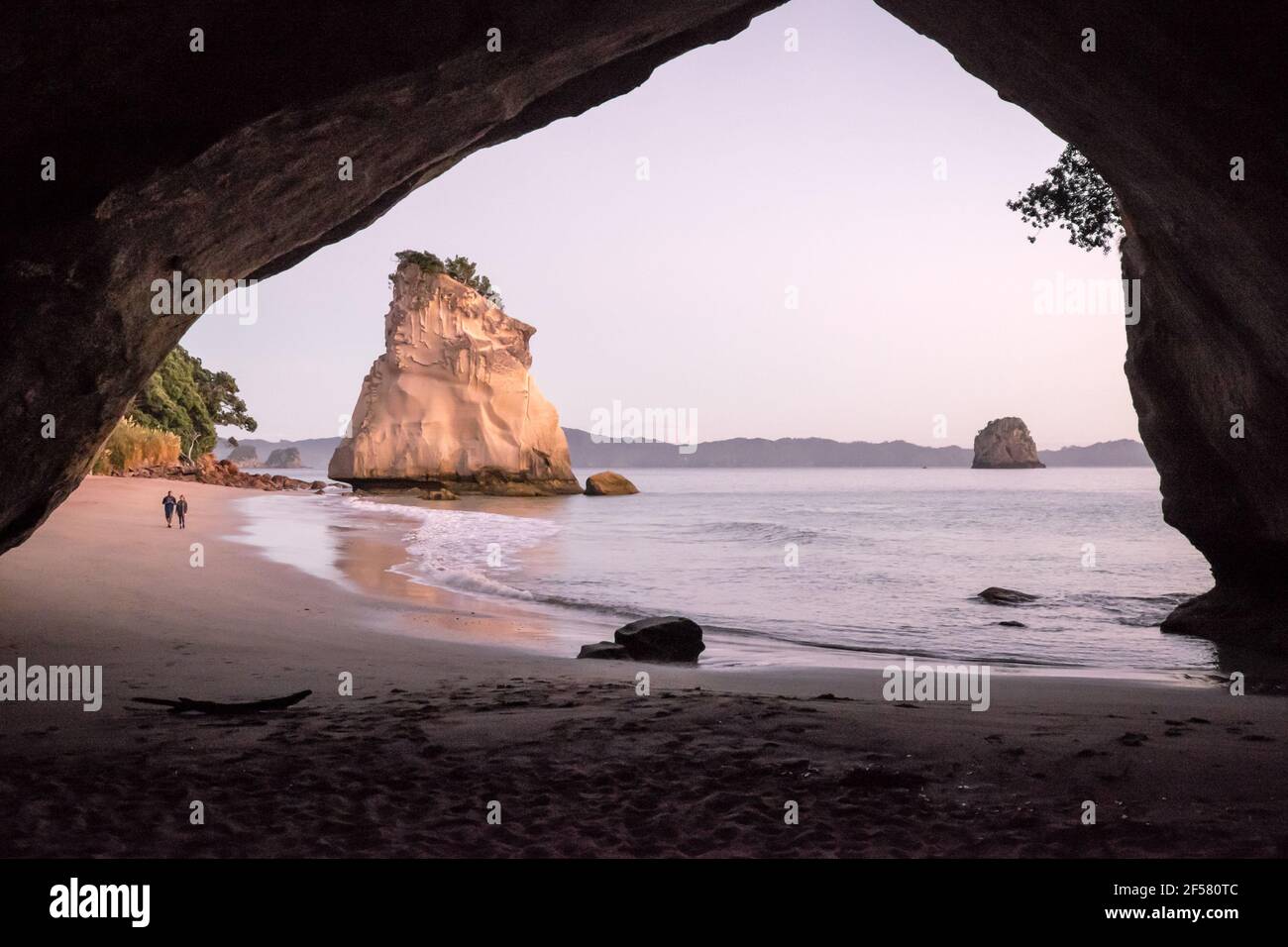 Touristen, die morgens am Strand in Cathedral Cove, Coromandel Peninsula, Neuseeland, spazieren gehen Stockfoto