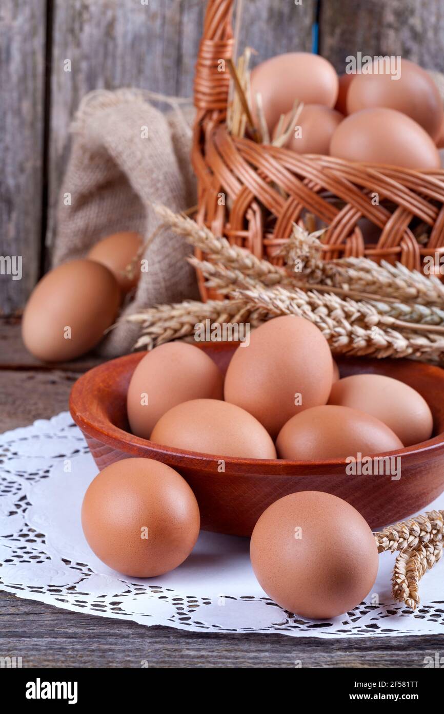 Eier in einer Holzschüssel mit einem kleinen Korb und Leinensack Hintergrund Stockfoto
