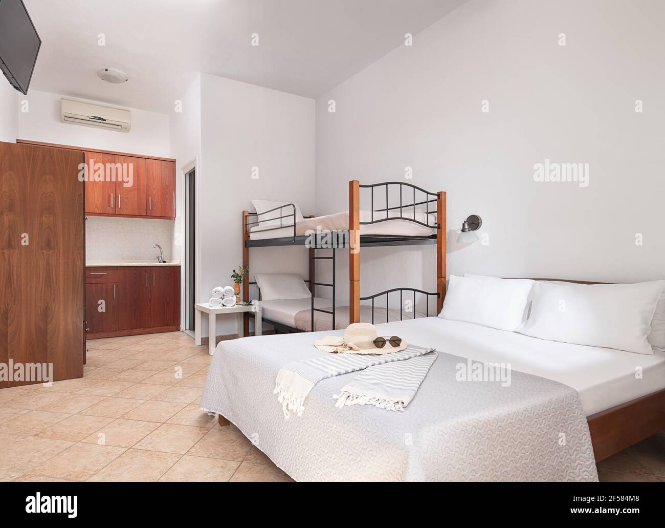 Weißes modernes Interieur von Familienanzug Schlafzimmer mit klassischen Doppelbett, Etagenbett mit Metalltreppen, hölzerne Küchenschränke in Einzelraum von kleinen Zimmer Stockfoto