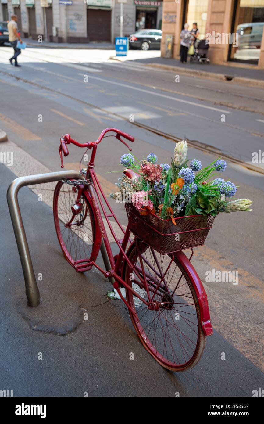 Vintage rosa Fahrrad mit EINEM Korb von Blumen geparkt an EINER Straße in Mailand, Italien Stockfoto