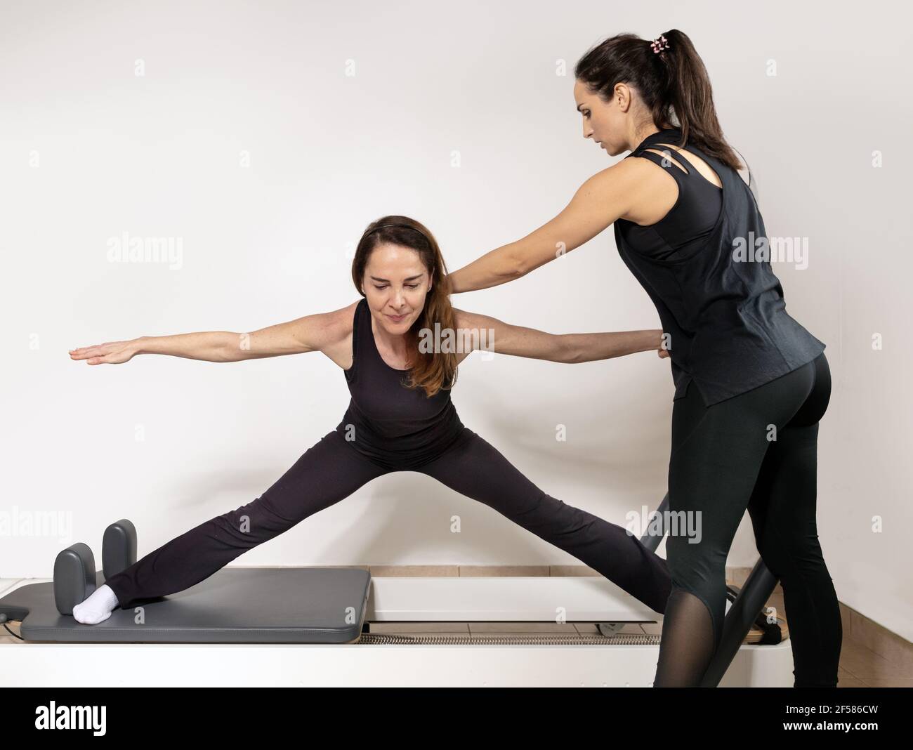 Eine Frau, die Übungen mit einem Pilates Personal Trainer praktiziert. Stockfoto