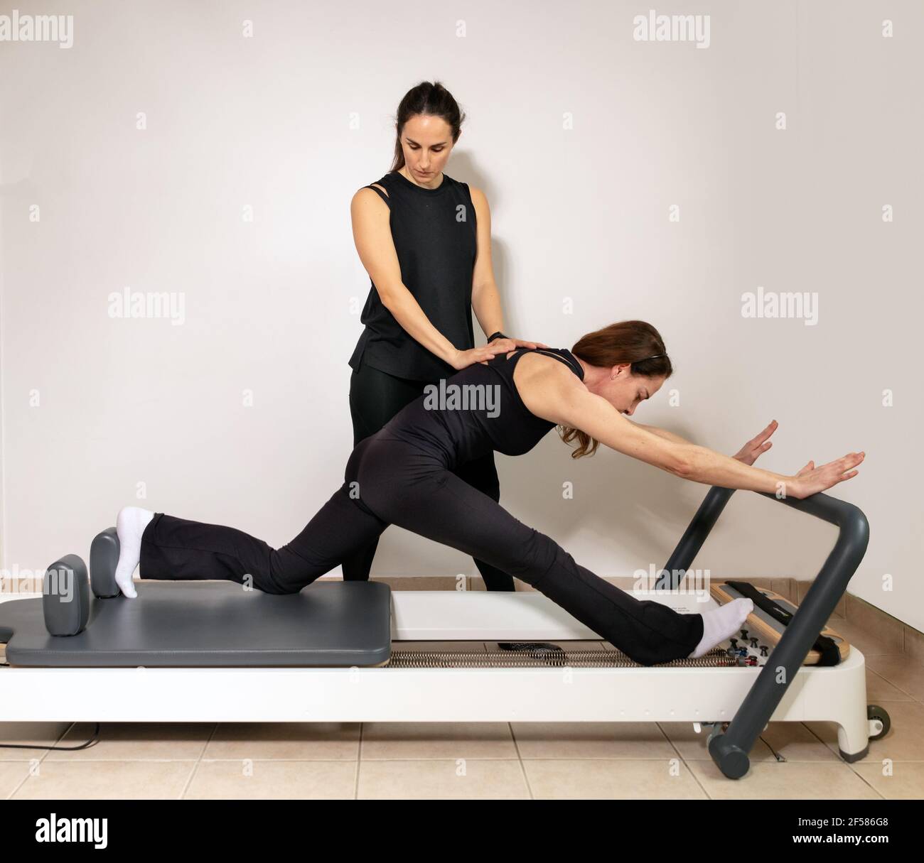 Eine Frau, die Übungen mit einem Pilates Personal Trainer praktiziert. Stockfoto