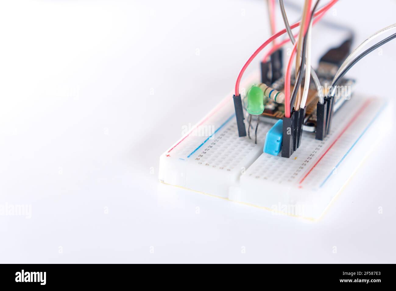 Elektronische Geräte, LEDs, Widerstände und Mikrocontroller auf einem Experimentierboard, um IoT-Projekte im Internet der Dinge auf weißem Hintergrund zu studieren. Stockfoto