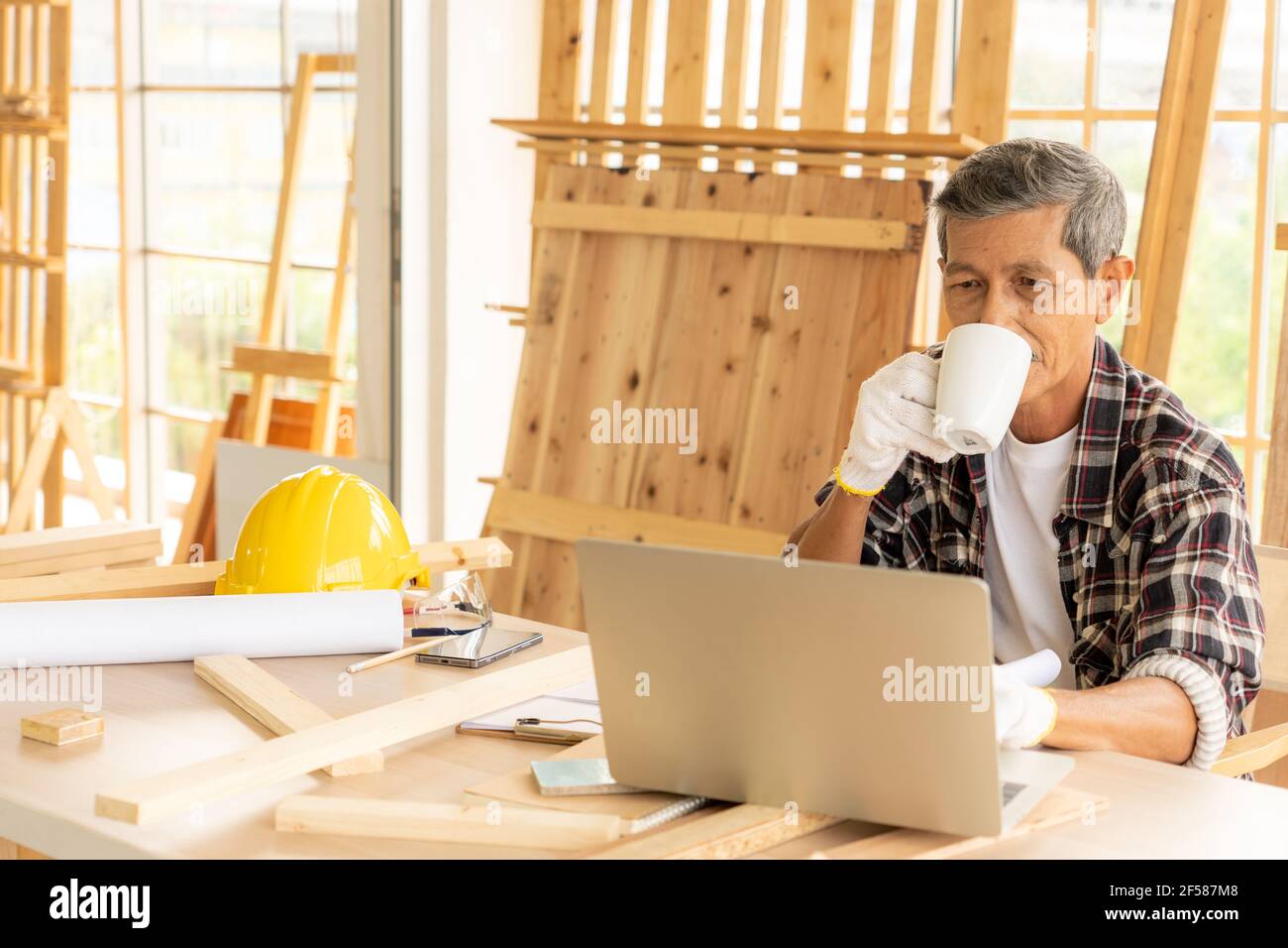Der ältere oder ältere beginnt seine neue Karriere als Zimmermann. Lernen und suchen Sie Informationen online mit Computern. Stockfoto