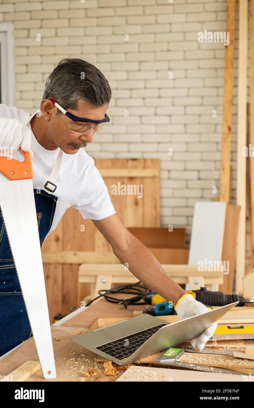 Der ältere oder ältere lernen neue Fähigkeiten, Lernen Sie ein Schreiner von Computern online zu werden. Stockfoto