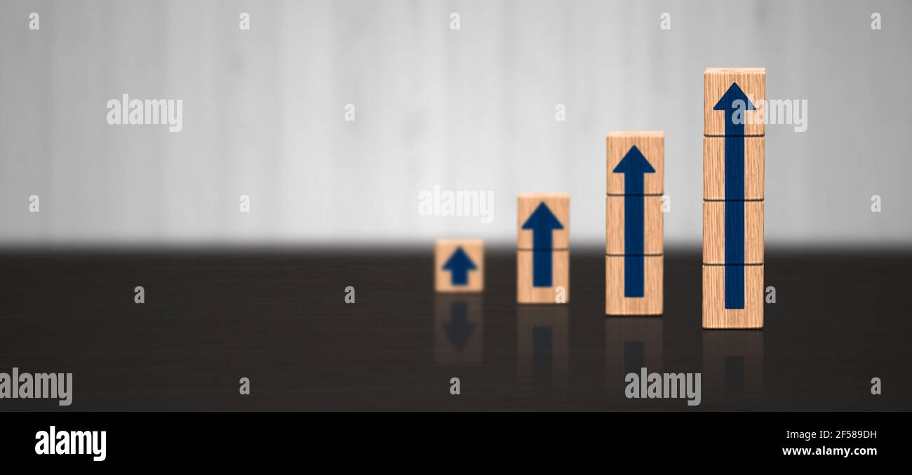 Geschäftswachstum und Produktivitätskonzept. Blauer Pfeil steigt in Holzblock auf. Holztreppe mit Pfeil nach oben. Panorama Holzhintergrund Stockfoto