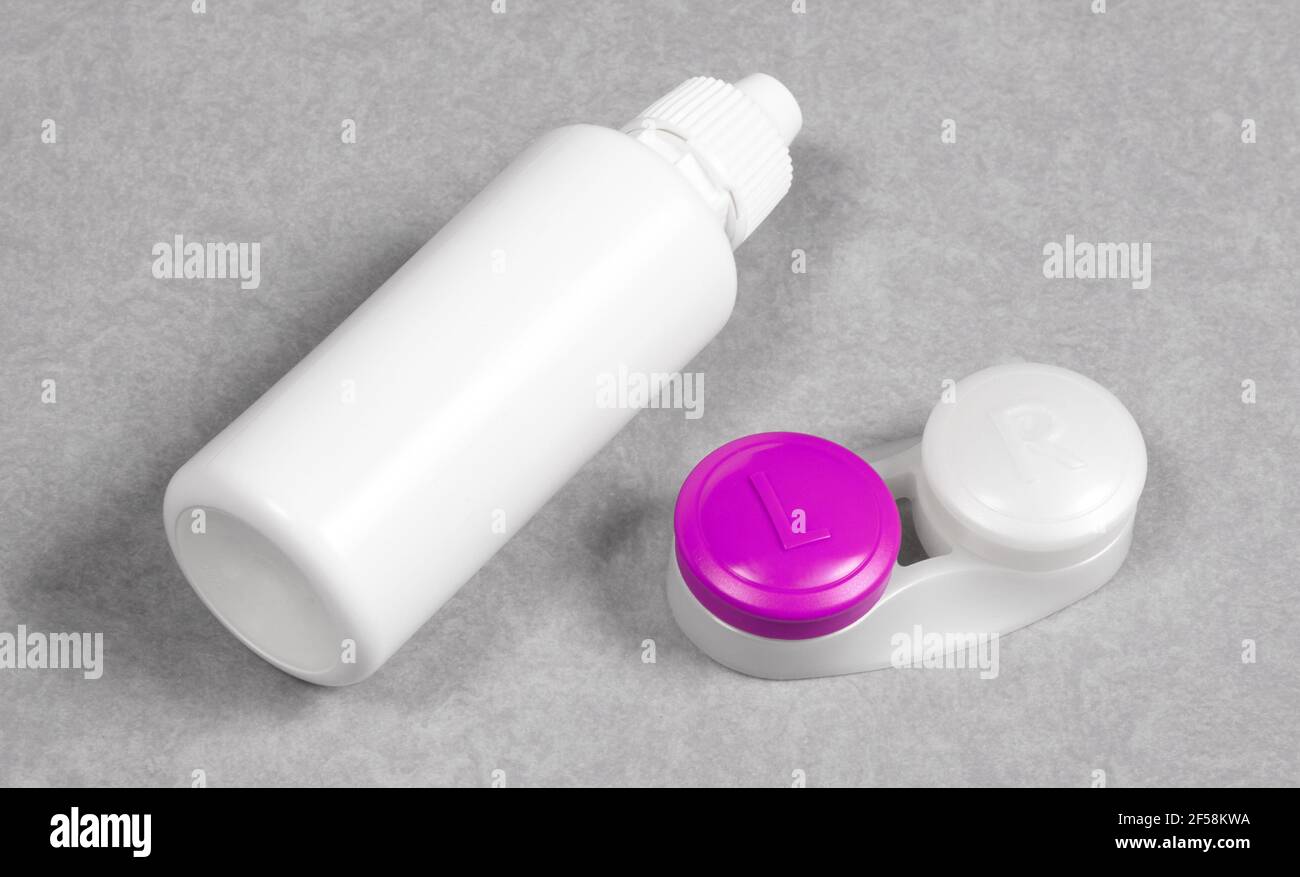 Rosa Kontaktlinsengehäuse und Flasche Lösung, isoliert auf grauem Hintergrund Stockfoto