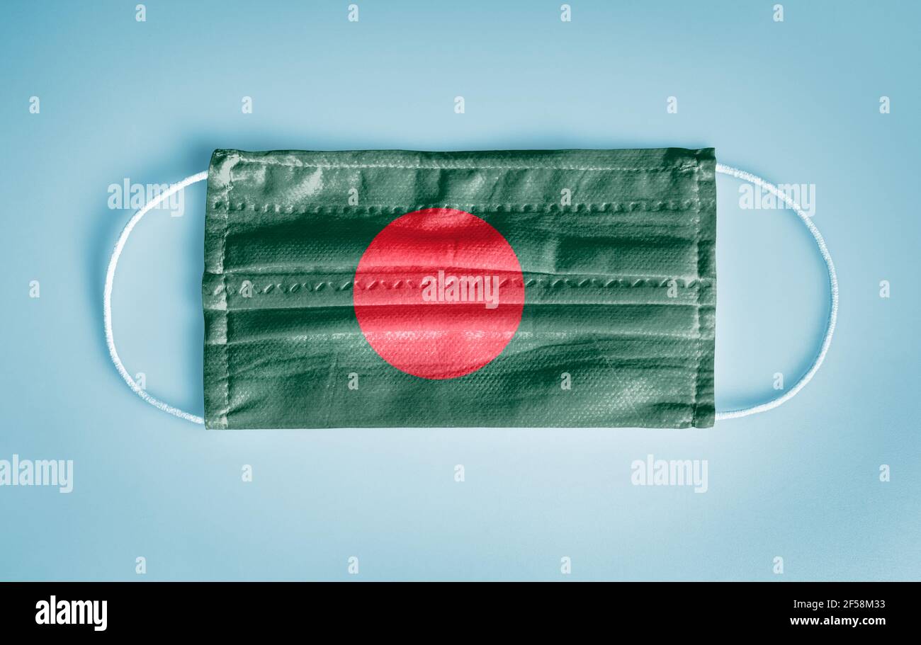 Covid-19 Coronavirus Schutzkonzept: Medizinische Einweg-Gesichtsmaske mit Bangladesch-Flagge auf blauem Hintergrund. DIE WHO empfiehlt die Verwendung der Maske aus Sicherheitsgründen. Stockfoto