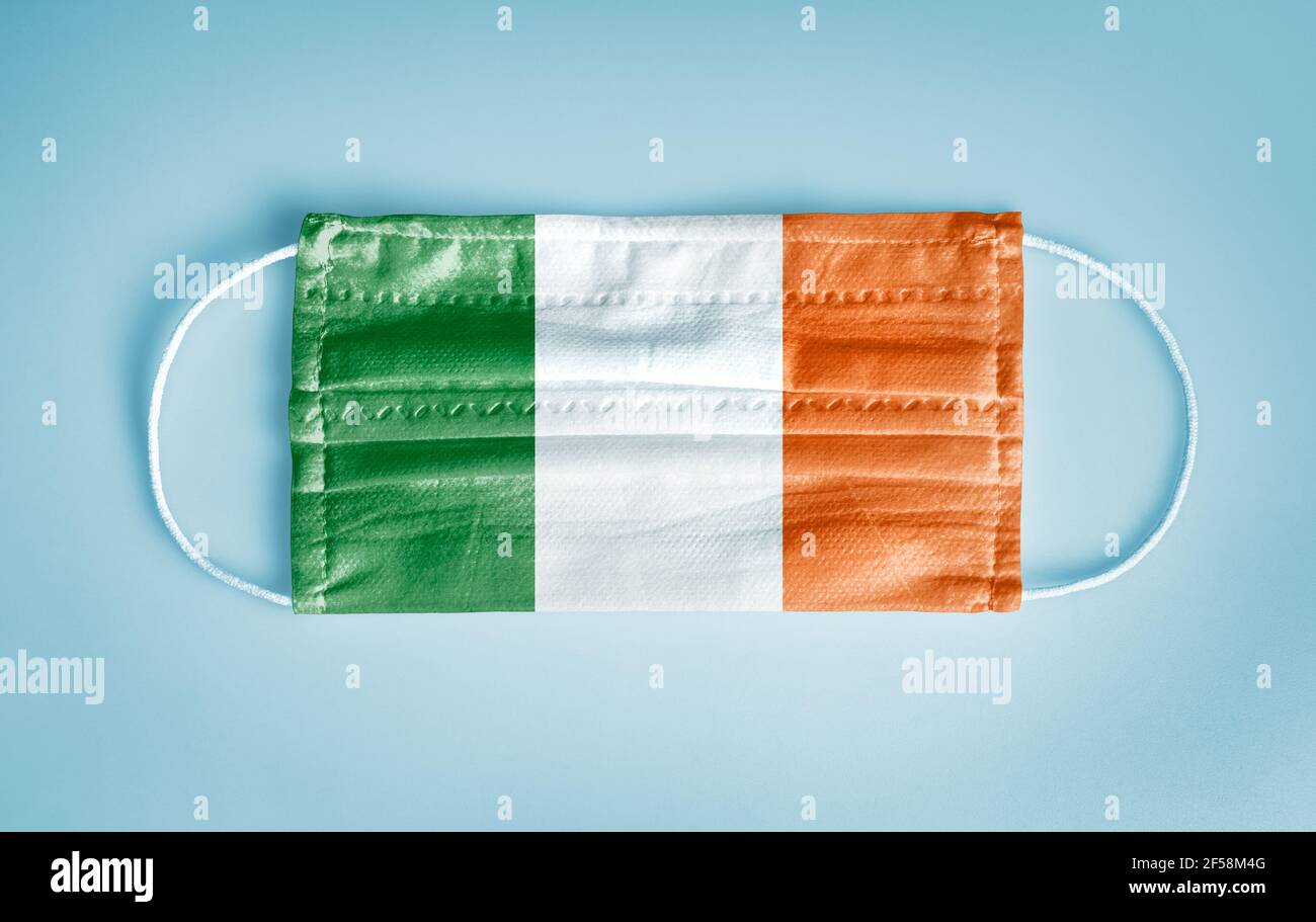 Covid-19 Coronavirus Schutzkonzept: Medizinische Einweg-Gesichtsmaske mit Irland Flagge auf blauem Hintergrund. DIE WHO empfiehlt die Verwendung der Maske aus Sicherheitsgründen. Stockfoto