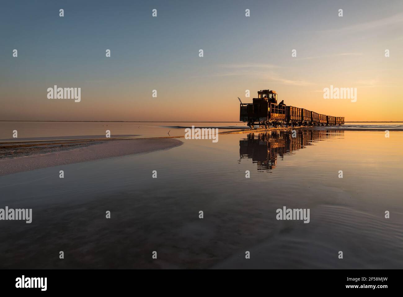 Herrliche Aussicht auf den Salzsee, Schienen, Zug auf dem Wasser und Reflexionen bei Sonnenuntergang. Lake Bursol, Altai-Region, Russland. Stockfoto