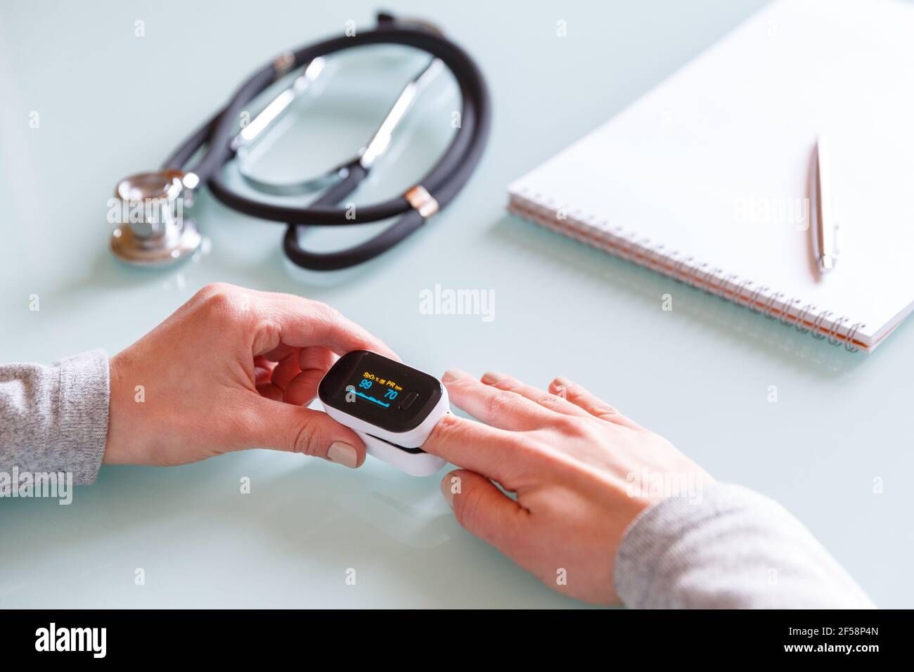 Weibliche Patientenhand zur Messung der Sauerstoffsättigung und des Pulses mit einem tragbaren Oximeter. Gesundheitskonzept Stockfoto