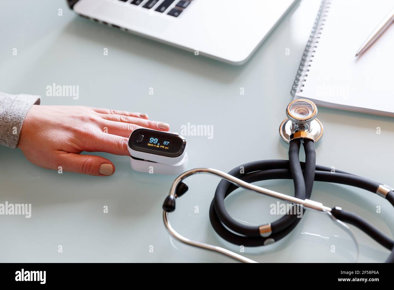 Weibliche Patientenhand zur Messung der Sauerstoffsättigung und des Pulses mit einem tragbaren Oximeter. Gesundheitskonzept Stockfoto