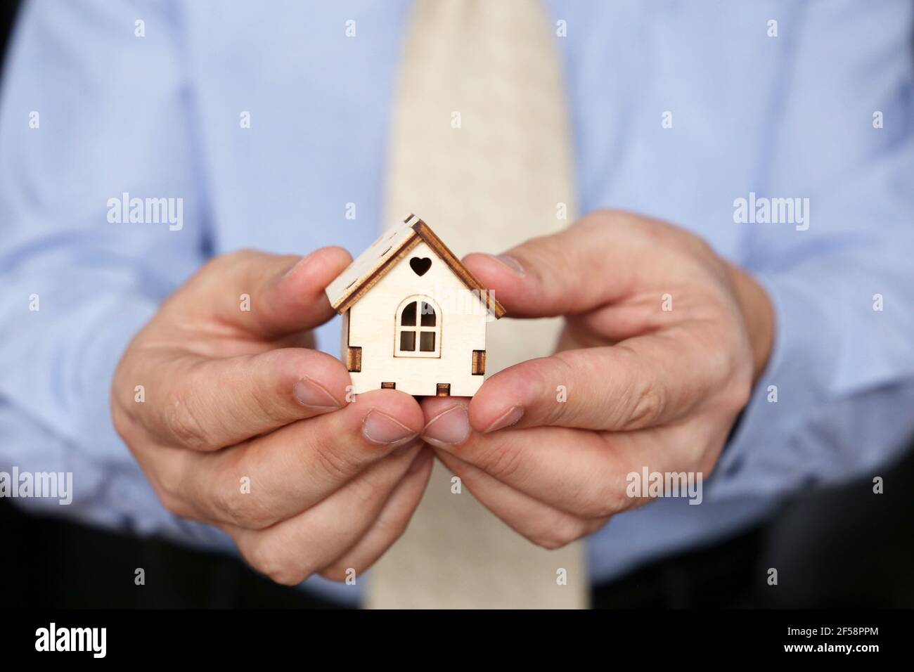 Immobilienmakler, Holzhaus in männlichen Händen. Mann in Bürokleidung mit Hausmodell, Kauf oder Vermietung zu Hause Stockfoto Immobilienmakler, Holzhaus in männlichen Händen. Mann in Bürokleidung mit Hausmodell, Kauf oder Vermietung zu Hause Stockfoto