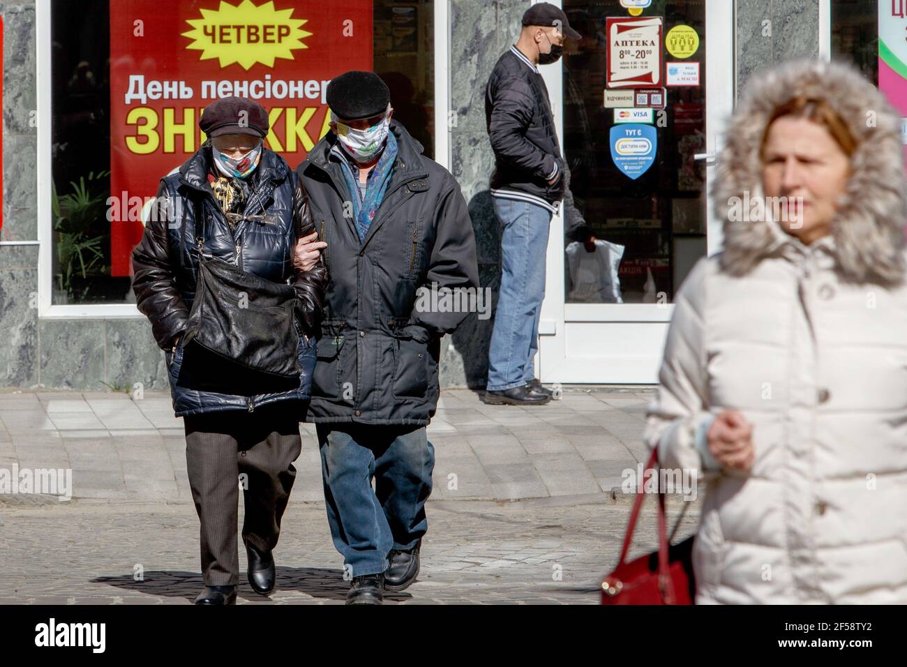 UZHHOROD, UKRAINE - 24. MÄRZ 2021 - EINE Frau und ein Mann mit Gesichtsmasken überqueren eine Straße, da die Stadt in der roten Zone unter adaptiver Quarantäneregulatio liegt Stockfoto