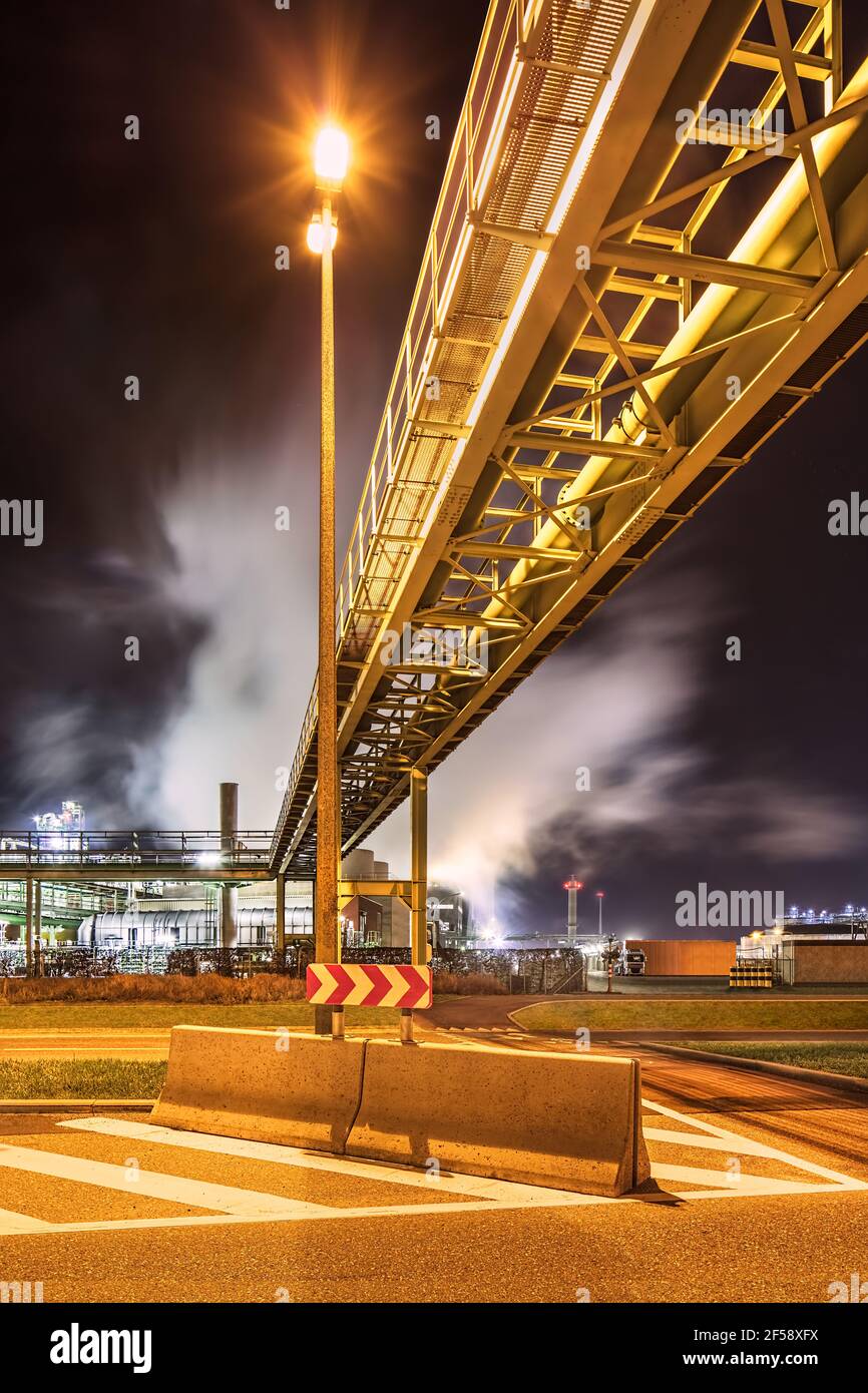 Nachtszene mit beleuchteter petrochemischer Produktionsanlage und Rohrleitungsbrücke, Antwerpen, Belgien. Stockfoto