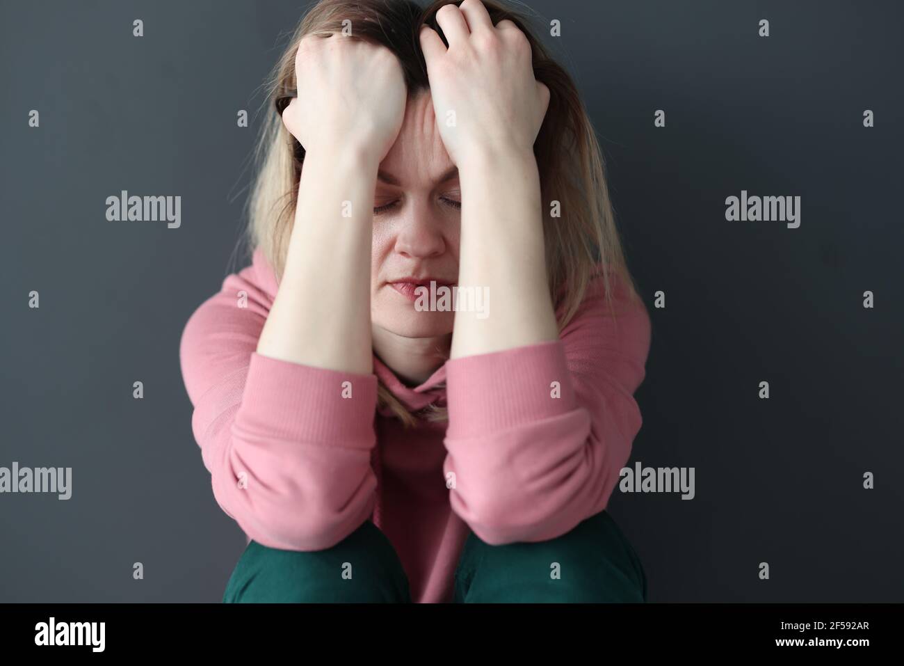 Traurige Frau mit geschlossenen Augen, die ihren Kopf bei sich hält Hände Stockfoto