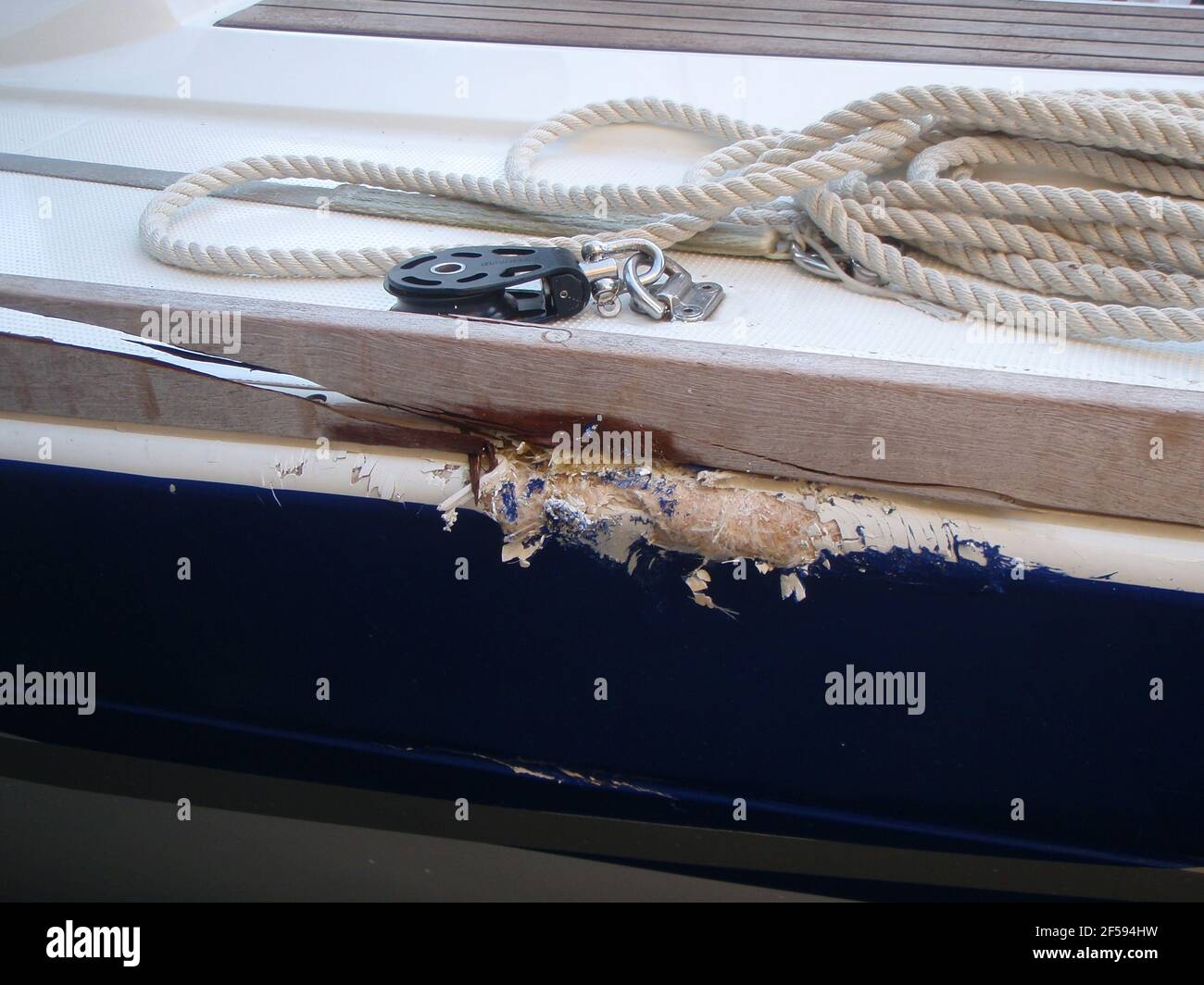 Schäden am Segelboot, hölzerne Zehenschiene beschädigt mit Spalt, Fiberglas-Rumpf und Deckschaden Stockfoto