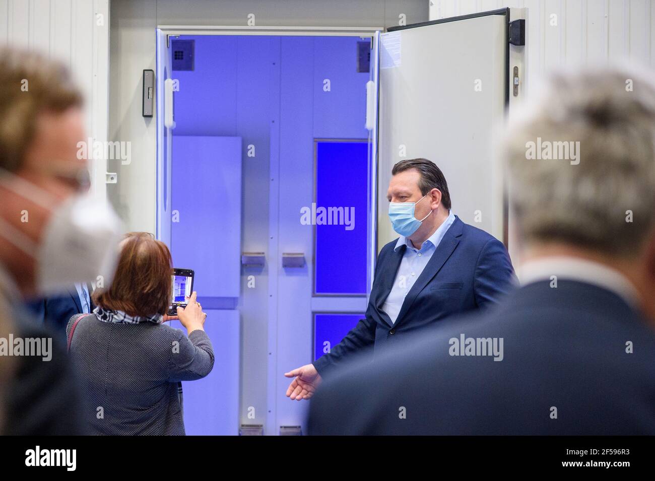 25. März 2021, Sachsen-Anhalt, Bitterfeld-Wolfen: Enrico Klauer (r), Geschäftsführer der Mecotec Gruppe, überreicht den mobilen Hybridcontainer 'MCF-8' der stellvertretenden Botschafterin der Philippinen in Deutschland, Lillibeth Pono (l), in der Werkshalle, die ein Foto des Kühlcontainers macht. Der Behälter kann rund eine halbe Million Impfstoffdosen bei minus 20 bis minus 80 Grad Celsius transportieren und lagern. Für 24 Stunden kann der Container ohne externe Stromquelle oder Betankung der integrierten Dieselgeneratoren auskommen. Der erste Container soll in AP auf die Philippinen geliefert werden Stockfoto