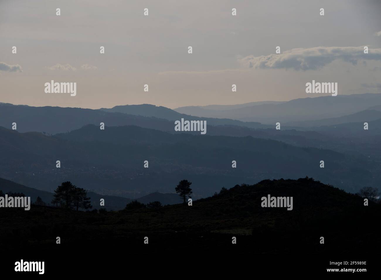 Bergformen und Kurven verblassen im Horizont in Ein düsterer Verlauf am Ende des Tages Stockfoto