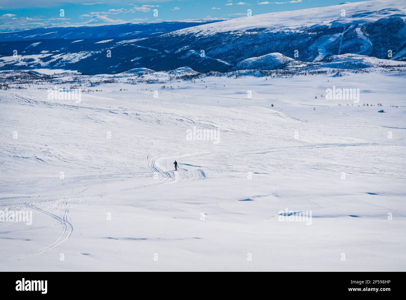 Person in der Ferne auf einem Pfad im tiefen Schnee auf dem Berghochland. Stockfoto