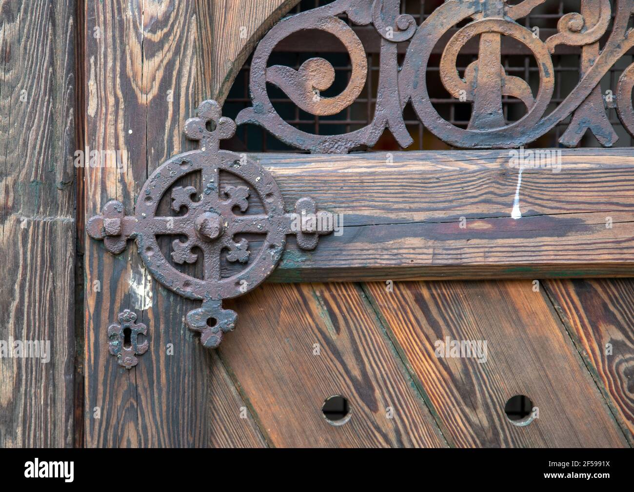 Kunstvolle Eisenarbeiten an einer braunen Holztür in Nahaufnahme. Stockfoto