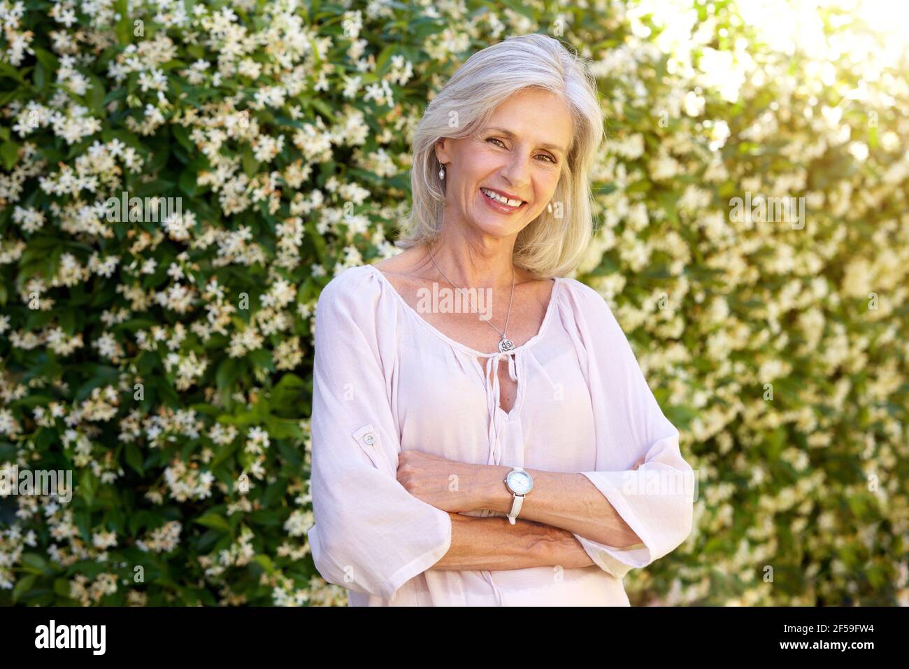 Porträt einer älteren Frau, die lächelt und im Frühling draußen steht Stockfoto