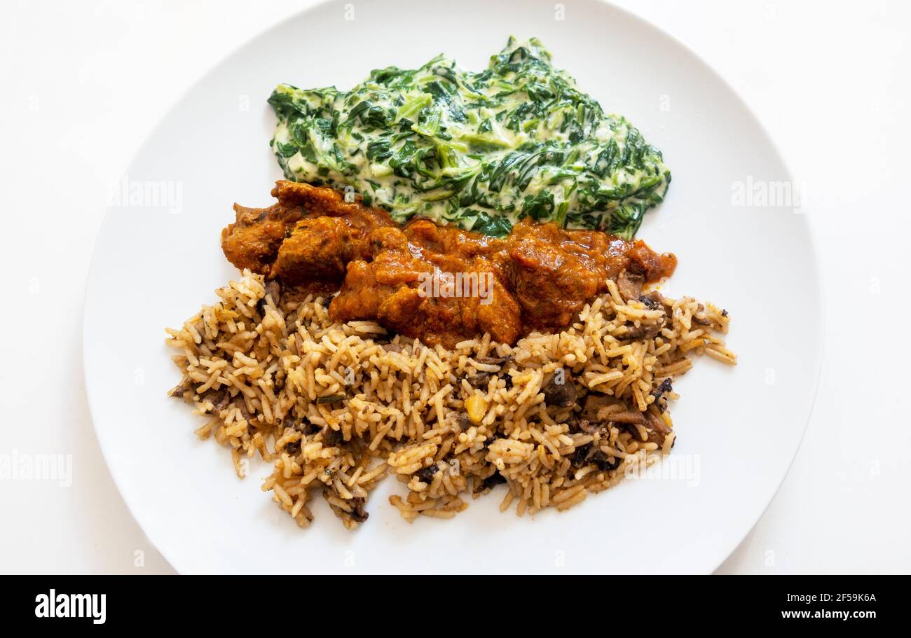 Lammcurry, Reis mit Pilzen und Spinat Stockfoto