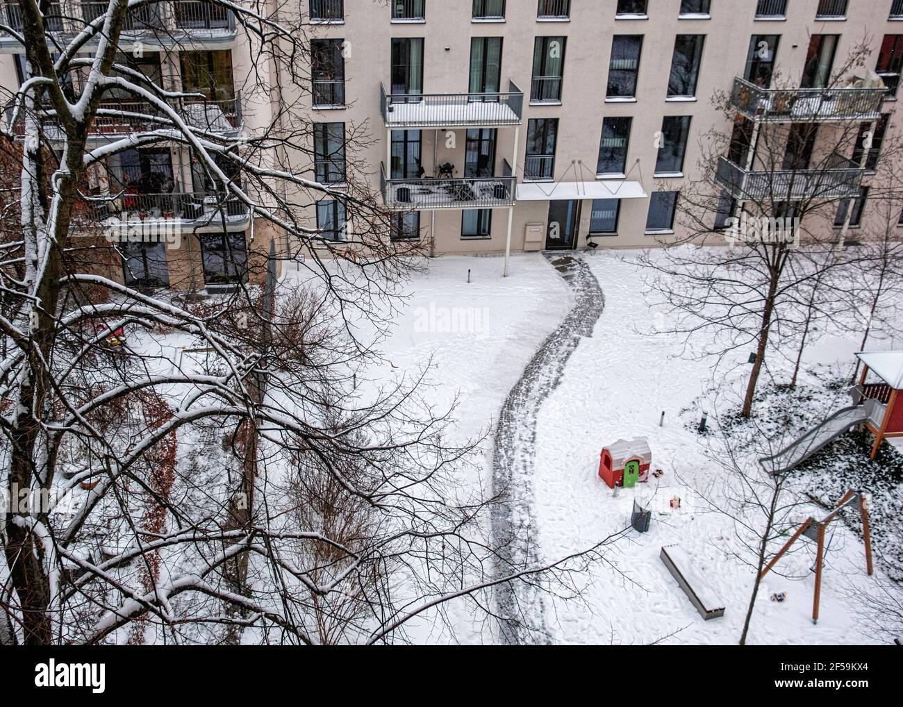 Verschneite Innenhof und Kinderspielplatz des Mehrfamilienhauses in Winter, Mitte, Berlin, Deutschland Stockfoto