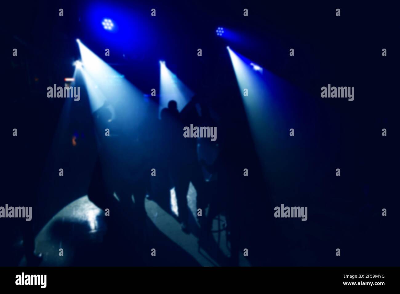 Weiße Scheinwerfer im Dunkeln mit blauer Clubbeleuchtung auf der Tanzfläche mit tanzenden Menschen in der Nähe der Bar. Nightlife-Konzept, verschwommener Hintergrund. Stockfoto