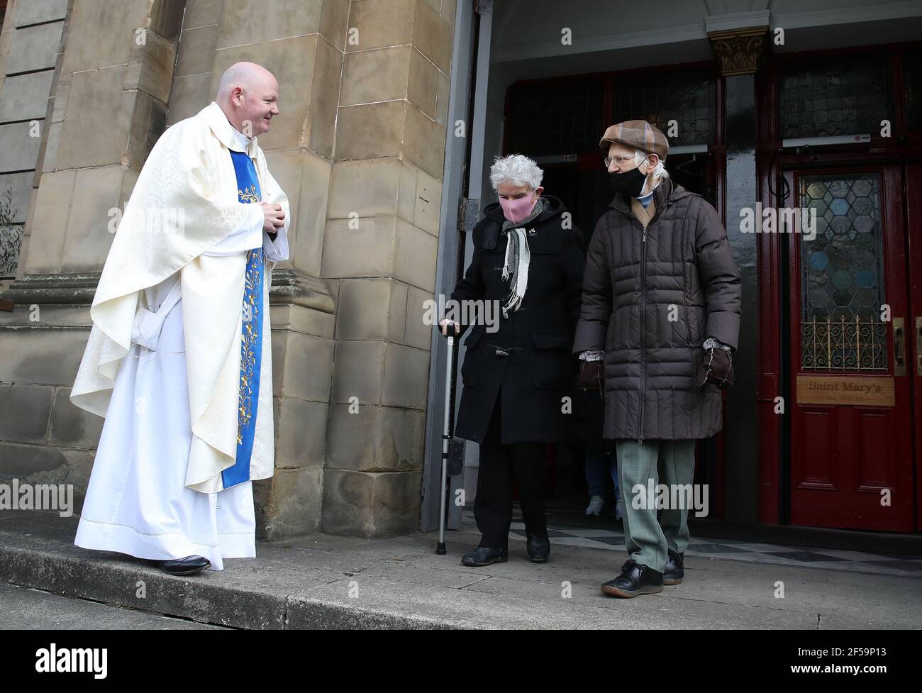 Canon Tom White begrüßt Gläubige, nachdem er einen Massengottesdienst in St. Mary's Catholic Chuch in Calton, Glasgow, gehalten hatte, nachdem Coronavirus-Vorschriften, die die Schließung von Kirchen in Schottland forcierten und öffentliche Gottesdienste kriminalisierten, vom Sitzungsgericht als rechtswidrig erachtet wurden. Kirchen sollen am Freitag unter Anleitung der schottischen Regierung geöffnet werden. Bilddatum: Donnerstag, 25. März 2021. Stockfoto