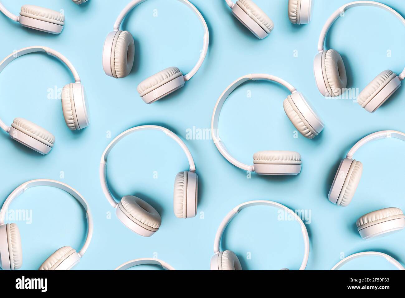 Draufsicht auf kreative Muster aus weißen kabellosen Kopfhörern Auf blauem Hintergrund Stockfoto
