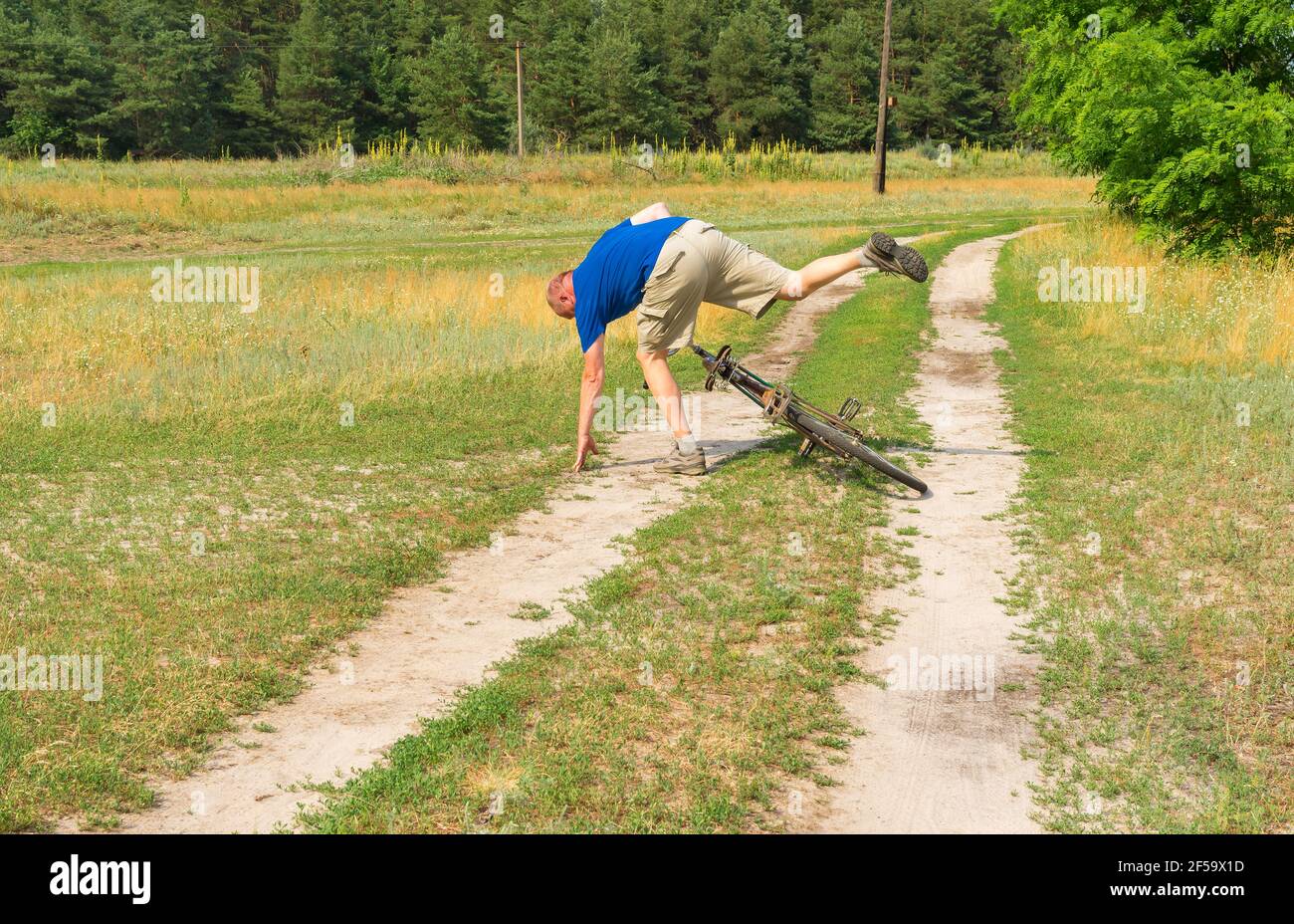 Reifer Mann fällt von einem alten Fahrrad auf einem Landstraße im ländlichen Dorf Mala Rublivka in der zentralen Ukraine Stockfoto