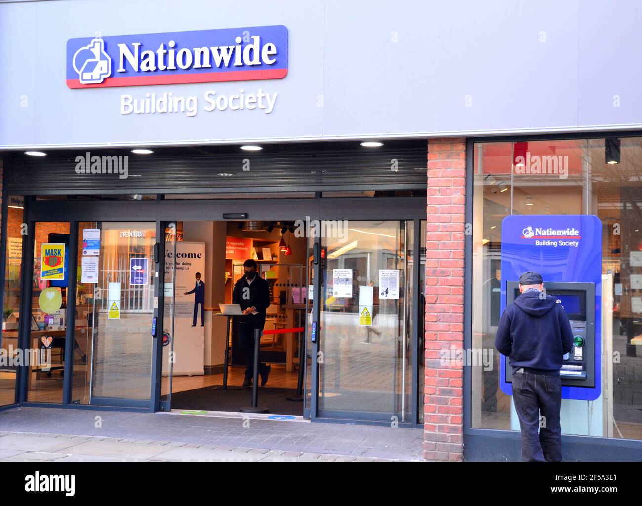 Außenansicht der Niederlassung der Nationwide Building Society in der Market Street, Manchester, England, Großbritannien. Mann am Geldautomaten. Mitarbeiter innen, um Kunden zu begrüßen. Stockfoto
