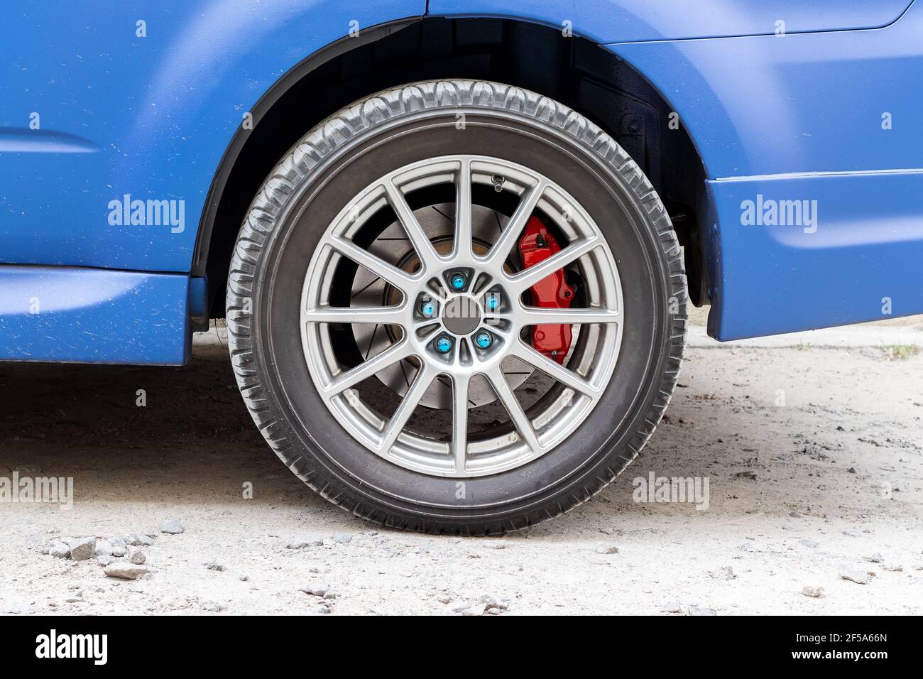 Stilvolles blaues Autorad mit rotem Bremssattel und 5-Mutter-Felge. Bremsanlage unterstützen Stockfoto