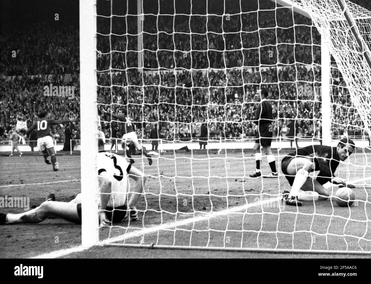 England gegen Westdeutschland WM-Finale 1966, Wembley-Stadion Englands Martin Peters dreht sich um sein 18th-Minuten-Tor mit Geoff Hurst und Roger Hunt zu feiern, während der Westdeutsche Hans Tilkowski den Ball aus dem Netz und Nummer 3 holt, Karl-Heiz Schnellinger bleibt auf dem Deck Foto von Tony Henshaw Archiv Stockfoto
