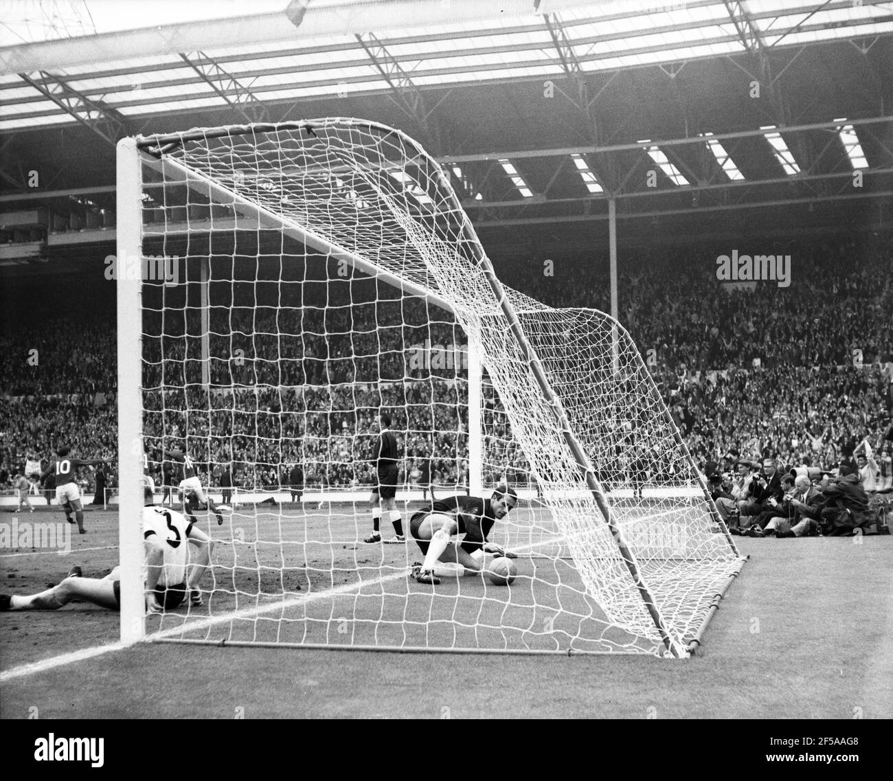 England gegen Westdeutschland WM-Finale 1966, Wembley-Stadion Englands Martin Peters dreht sich um sein 18th-Minuten-Tor mit Geoff Hurst und Roger Hunt zu feiern, während der Westdeutsche Hans Tilkowski den Ball aus dem Netz und Nummer 3 holt, Karl-Heiz Schnellinger bleibt auf dem Deck Foto von Tony Henshaw Archiv Stockfoto