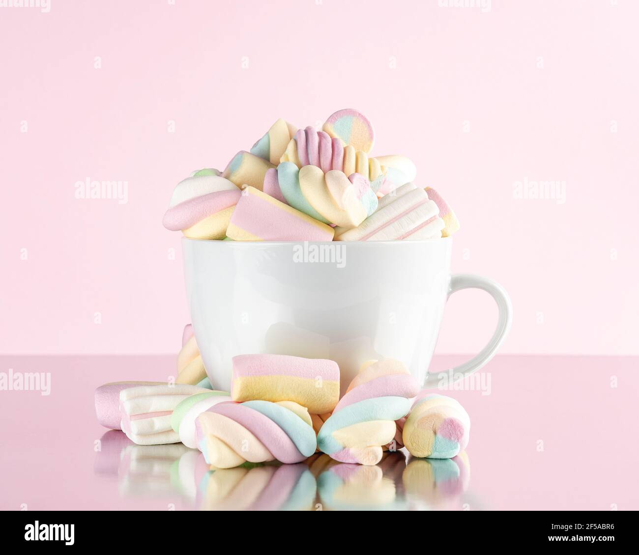 Marshmallows bunte Kaubonbons in einer Tasse auf rosa Hintergrund. Sweet Holiday Food Konzept. Stockfoto