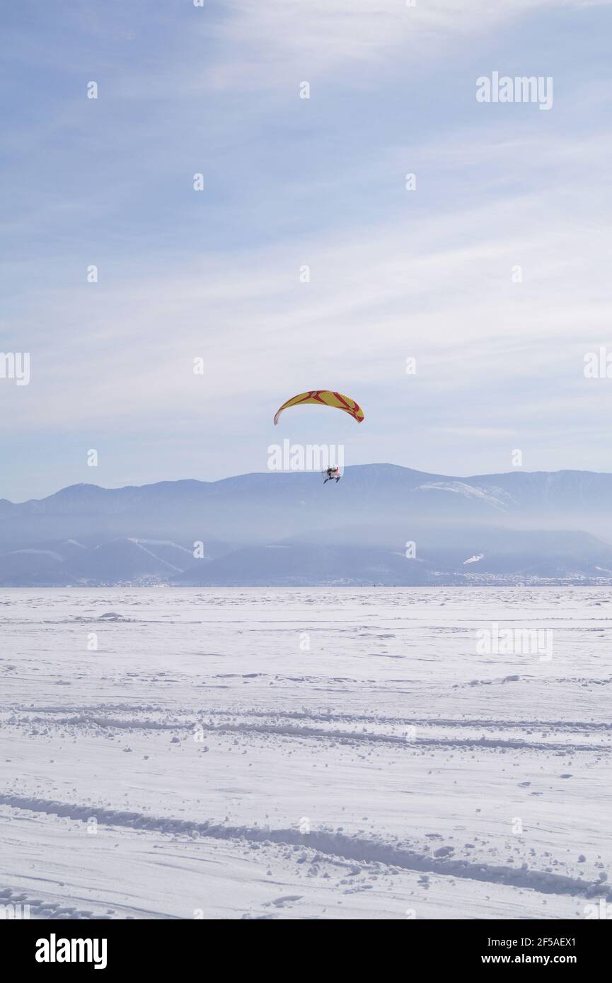 Ein Mann von 40-45 Jahren fliegt auf einem Gleitschirm Über dem Eis von L Stockfoto