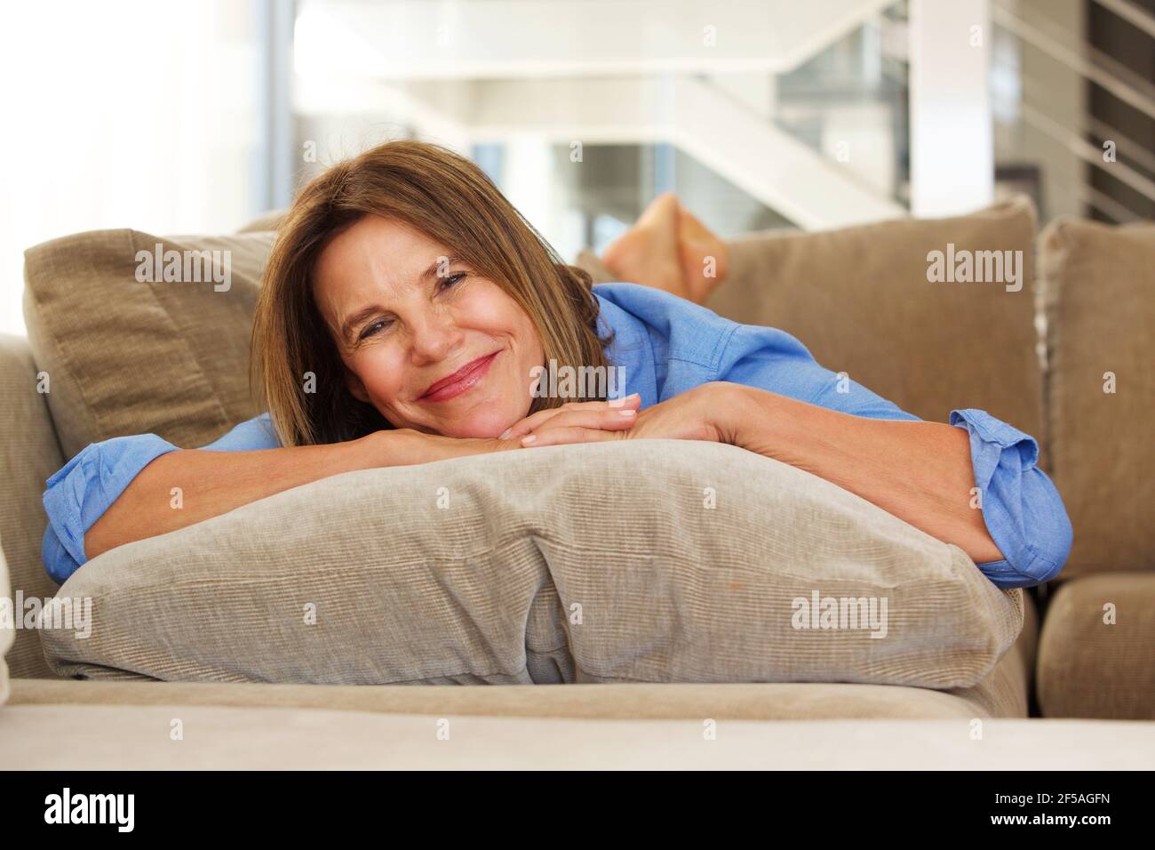 Porträt einer lächelnden älteren Frau, die sich zu Hause auf dem Sofa entspannt Stockfoto