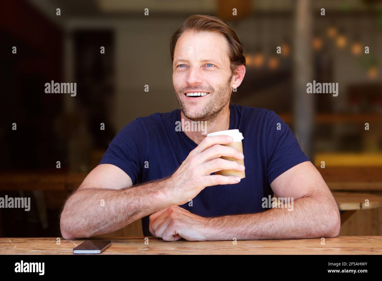 Portrait von coolen Mann mittleren Alters lächelnd mit Kaffeetasse Im Café Stockfoto