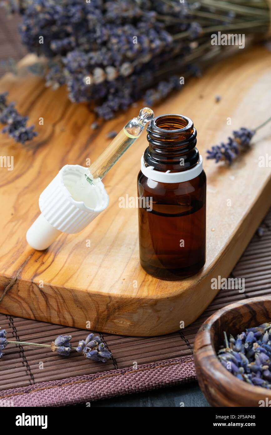 Bio-Kosmetikkonzept, Glasflasche mit Öl, Pipette und Lavendelblüten auf hellem Holzhintergrund Stockfoto