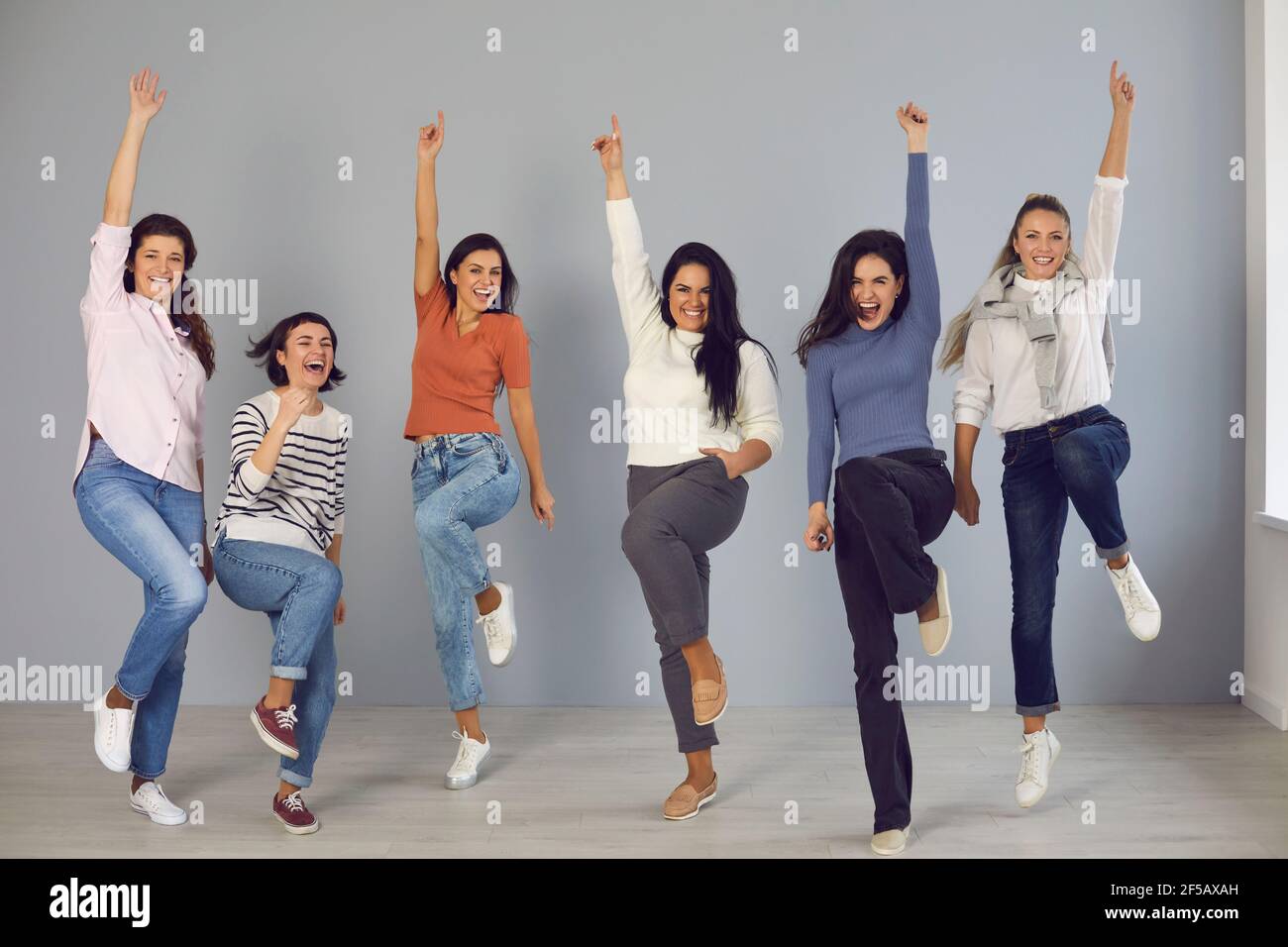 Gruppe von glücklichen selbstbewussten jungen Frauen springen vor Freude und Wir feiern den Erfolg des Teams Stockfoto